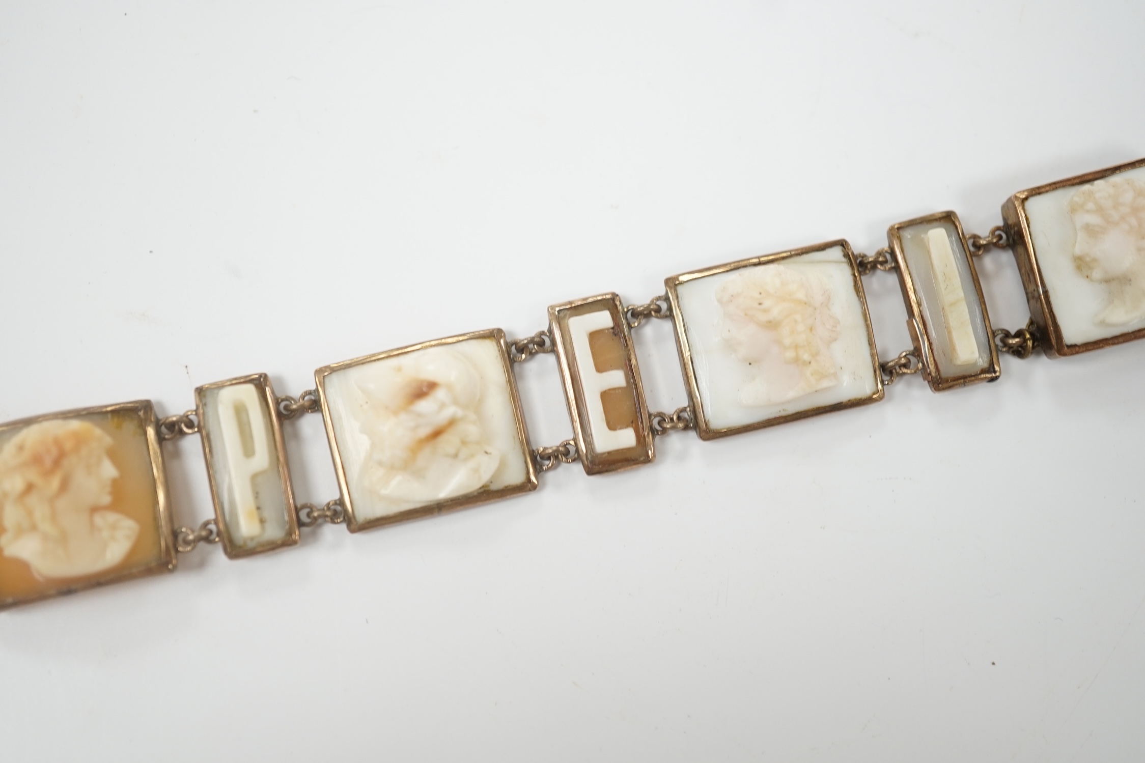 A 19th century Italian? yellow metal overlaid and cameo shell set bracelet, with panels of letters spelling 'Pompei' and panels of busts carved to dexter and sinister, (a.f.), overall 16.8cm.